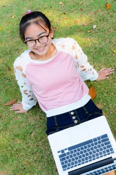 Cute girl is happy with notebook on grass in park