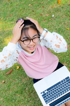 Cute girl is happy with notebook on grass in park