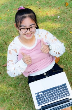 Cute girl is happy with notebook on grass in park