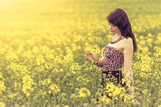 Attractive genuine young girl enjoying the warm summer sun in a wide green and yellow meadow. Part of series.