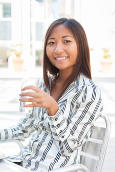 Portrait of an smiling asian girl drinking a glass of water