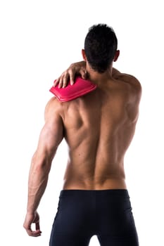 Back of muscular young man with shoulder pain, holding hot water bottle, isolated on white