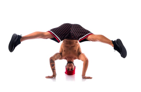 Athletic trendy shirtless young man in a hat doing a break dance routine isolated on white
