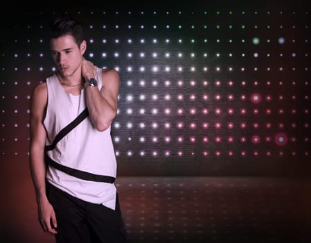 Hip young man standing on dark flashy background, looking to a side. Large copyspace
