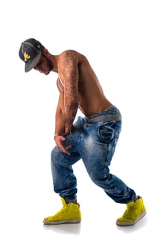 Athletic trendy shirtless young man in a hat doing a break dance routine isolated on white