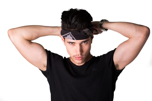 Handsome young man tying a bandanna around his head in the form of a headband as he stares at the camera with a seductive smouldering look, isolated on white
