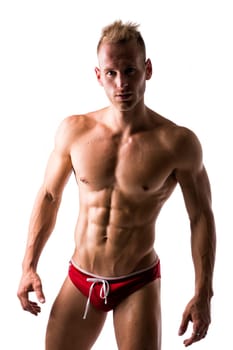Male swimmer standing with confidence showing off his muscular physique on white background