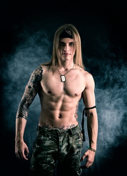 Shirtless male model wearing a bandanna smiling on smoky background