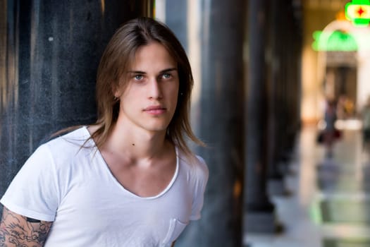 Handsome Long Hair Man on White Shirt Standing Besides Hallway