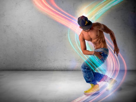 Athletic trendy shirtless young man in a hat doing a break dance routine surrounded by colorful light streaks