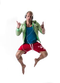 Hip young man jumping in the air giving thumbs up on white background