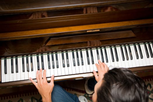 Male hands playing piano indoors inside house, shot from above