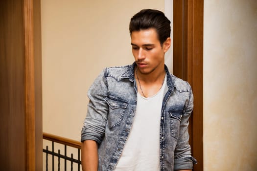 Attractive young man indoors, leaning against door jamb