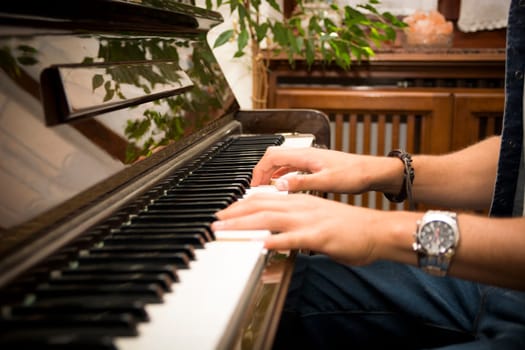 Male hands playing piano indoors inside house