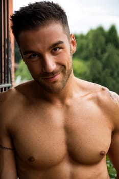 Handsome shirtless young man outdoor, smiling at camera