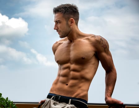 Handsome shirtless muscular young man outdoor, looking away