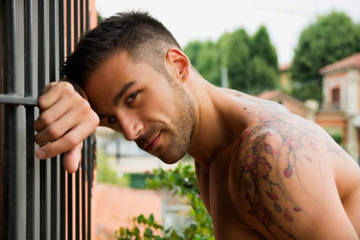 Handsome shirtless young man outdoor, looking at camera