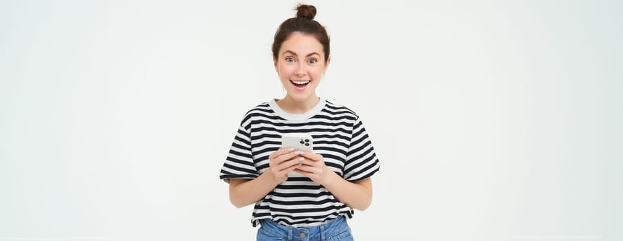 Technology and people concept. Young woman with mobile phone, smiling, using smartphone app, social media application, isolated over white background.