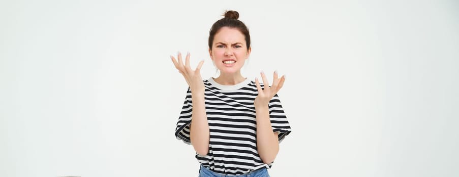 Portrait of angry woman shouting and shaking hands, losing her temper, arguing, standing over white background.