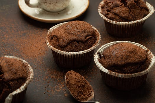 Chocolate and cocoa browny muffins with coffee cappuccino in cup angle view on brown rustic stone background, sweet homemade dark chocolate cupcakes.