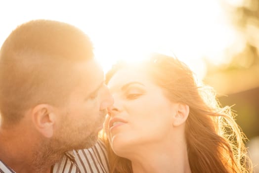 Couple kissing at sunset - photographed against sun