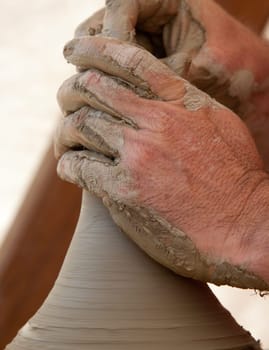 Close-up of potter's hands working  over potter's wheel with a little pot