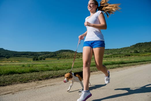 Beautiful teenage girl jogging with her pet (beagle dog) in nature