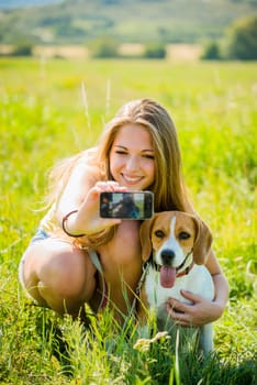 Young woman taking photo of herself and her pet with mobile phone camera