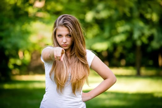 Cheeky teen girl showing to the front with finger - outdoor in nature