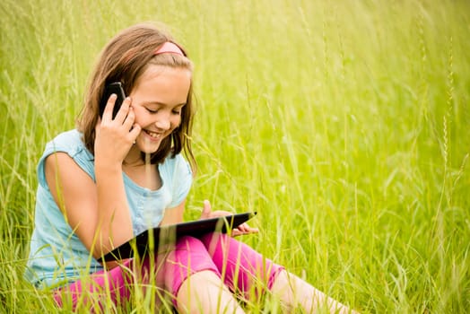 Smiling child watching movie on tablet outdoor in nature