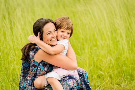 Mother and child are hugging and embracing outdoor in nature