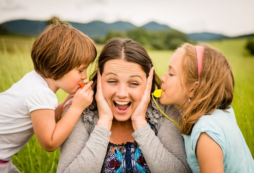 Children blowing whistles to mother's ears- outdoor in nature
