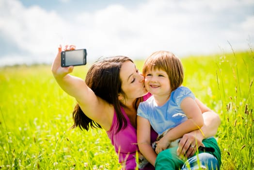 Young woman taking photo with her smart-phone camera of herself, her daughter and kitten