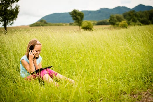 Smiling child watching movie on tablet outdoor in nature