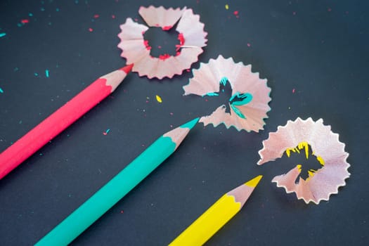 Different color pencils shavings on dark background, stock photo