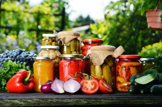 Jars of pickled vegetables in the garden. Marinated food.