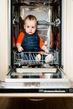 Cute baby sitting in empty dishwasher with tablet