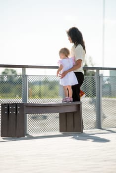Mother with little girl in white dress looking somewhere to distance