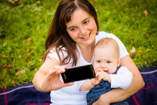 Mother taking picture of her and baby with smartphone camera