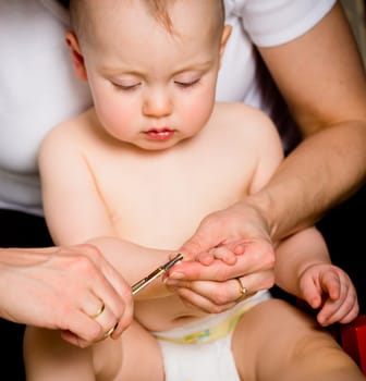 Mother cutting nails on hands of her baby - sitting on floor in bathroom