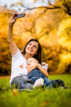 Mother taking picture of her and baby with smartphone camera
