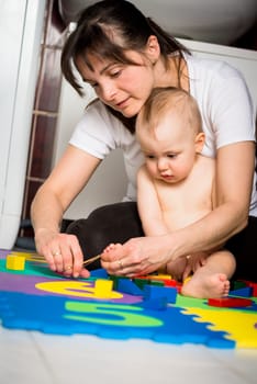 Mother cutting nails on feet of her baby - sitting on floor in bathroom