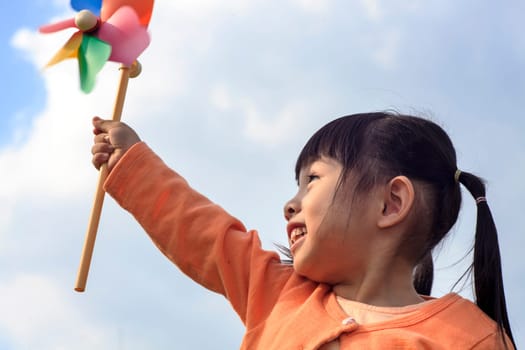 cute little girl on grass in summer day holds windmill for adv or others purpose use