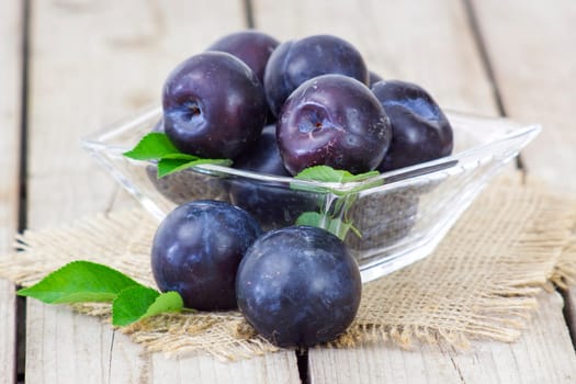fresh plums in a bowl on old wooden background
