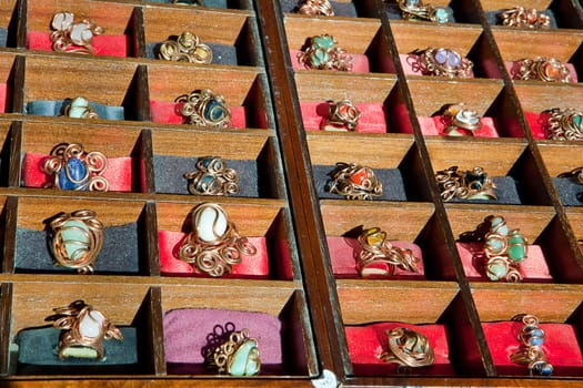 Colorful assortment of jewelry on wooden display full of rings