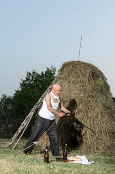 Senior farmer using scythe to mow the lawn traditionally.
