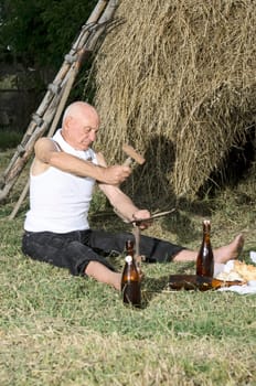 Senior farmer using scythe to mow the lawn traditionally.