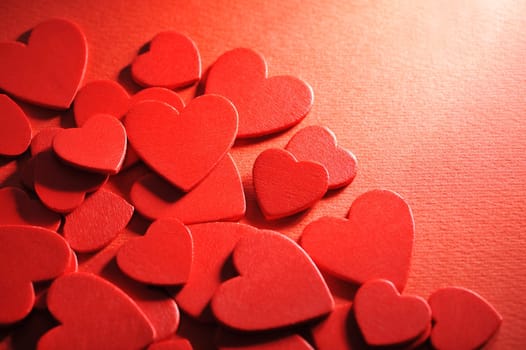 Many small red wooden hearts on a red background