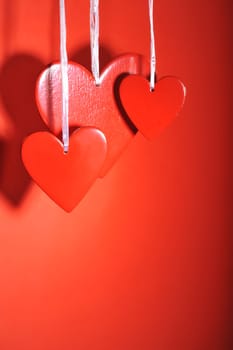 three red wooden hearts against a red background