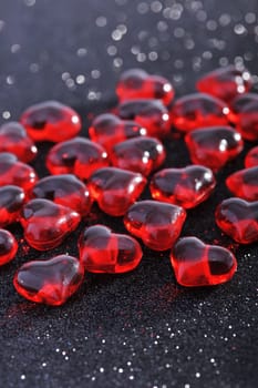 Red glass hearts on a black glitter background
